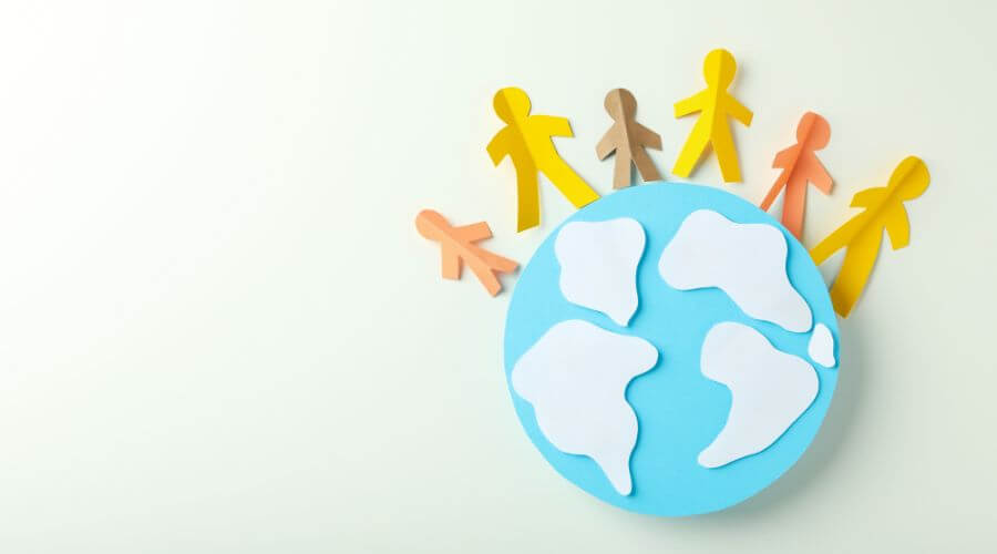 Image showing paper cutouts of people holding hands, arranged in a circle around a globe, symbolizing collaboration